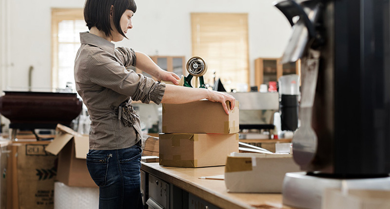 A person carefully packing parcels at a workbench
